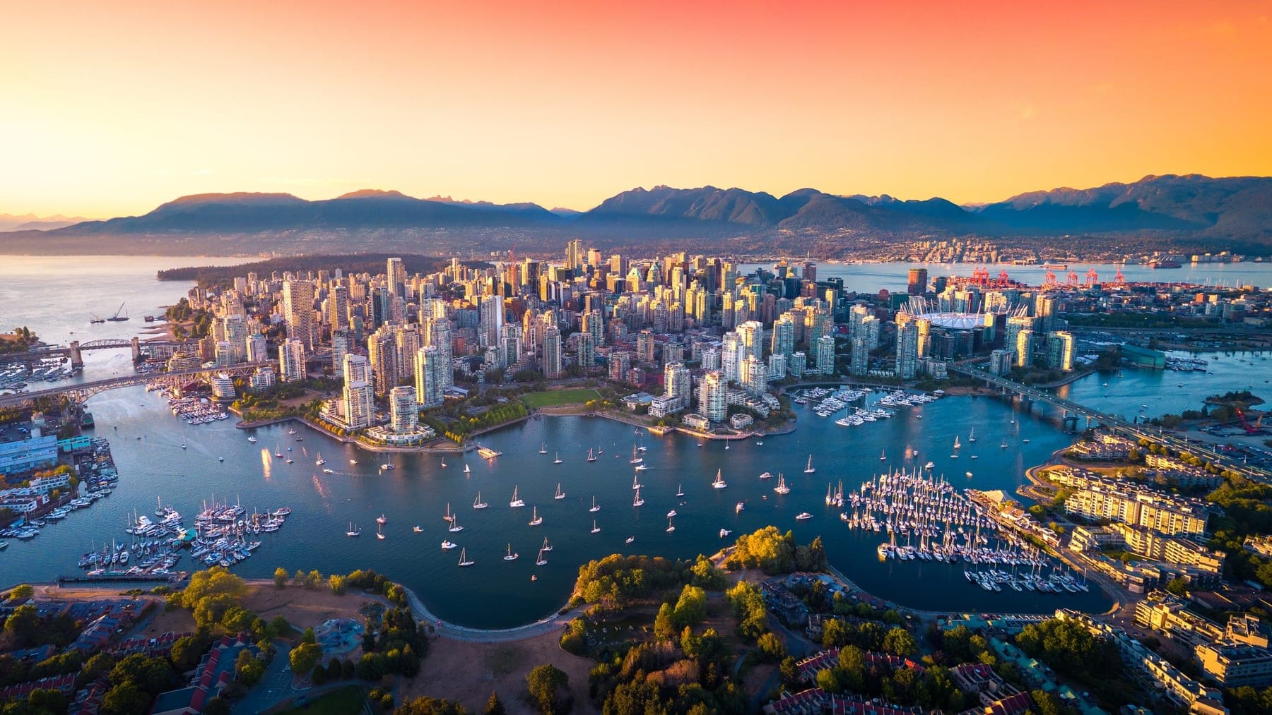 Downtown Vancouver from the air at sunset, with False Creek sailboats, Stanley Park, and the North Shore mountains