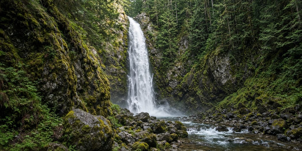 Waterfall dropping through a forested canyon in Mission