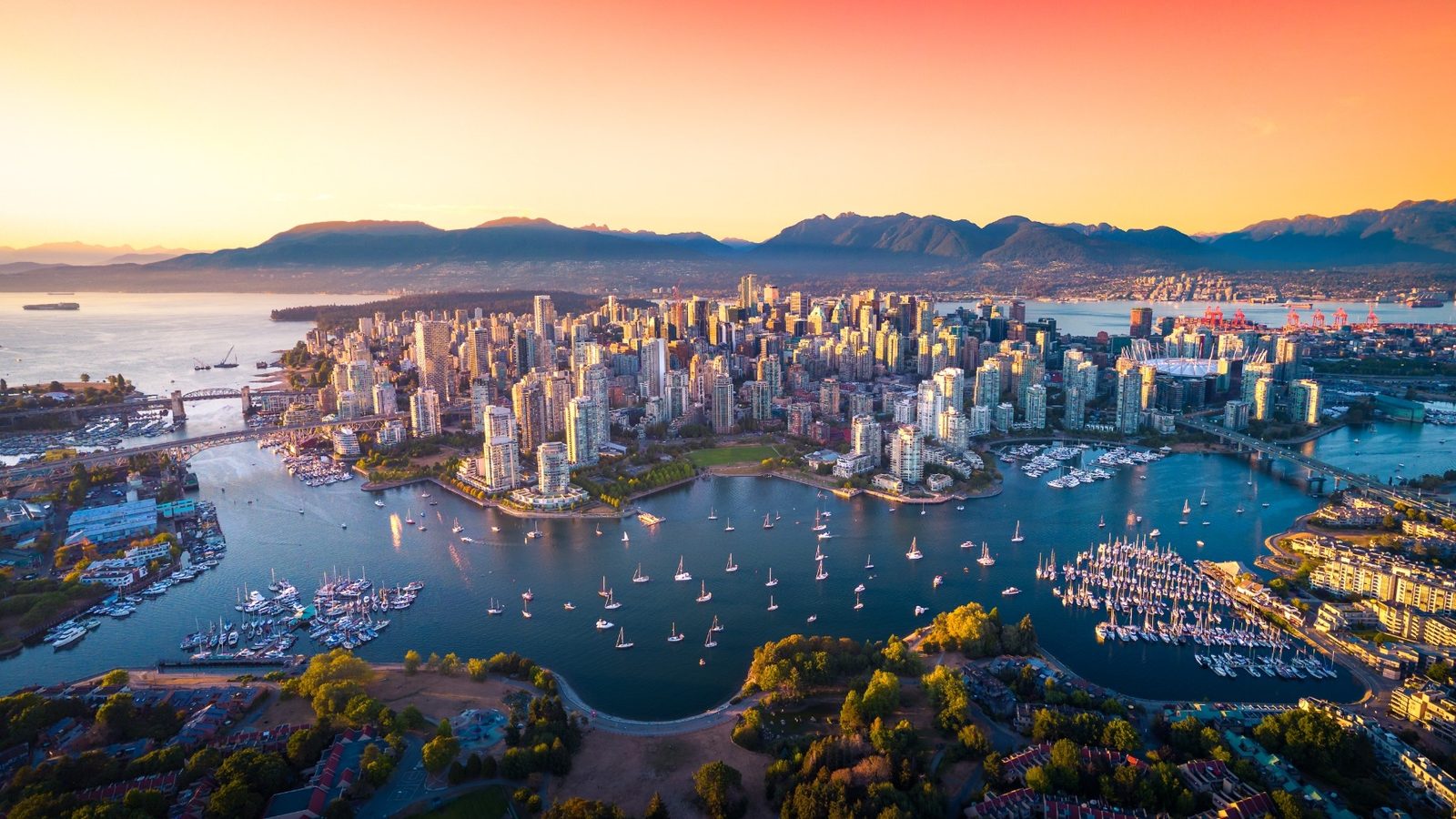 Downtown Vancouver from the air at sunset, with False Creek sailboats, Stanley Park, and the North Shore mountains